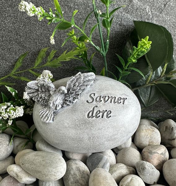 Gravpynt rund stein, med due og teksten "Savner dere"